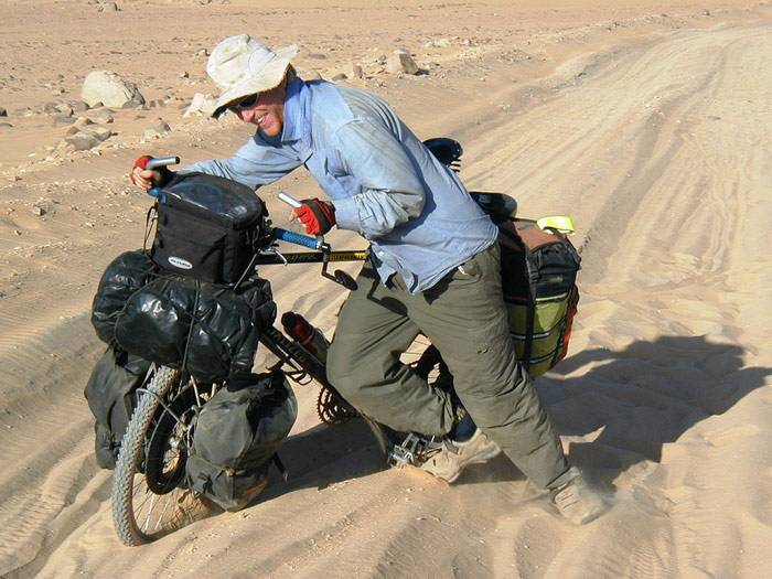 Alastair pushing a bike through the Nubian Desert in Sudan