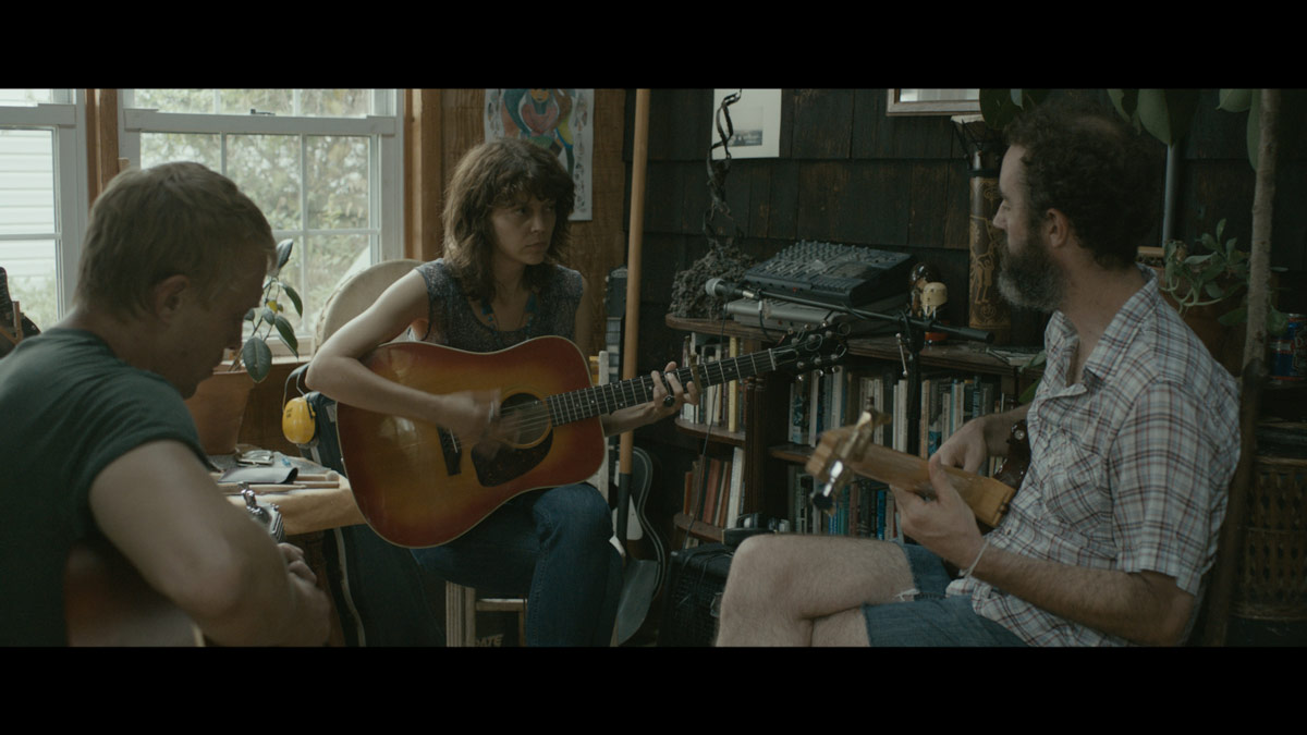 still from I Used To Be Darker: Kim Taylor playing guitar with bandmates