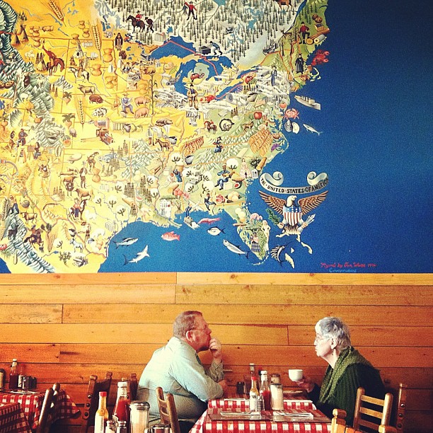 couple having breakfast with America mural on the wall behind