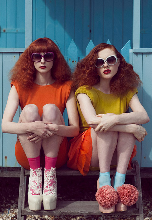 two young women sitting on steps with sunglasses and bright dresses