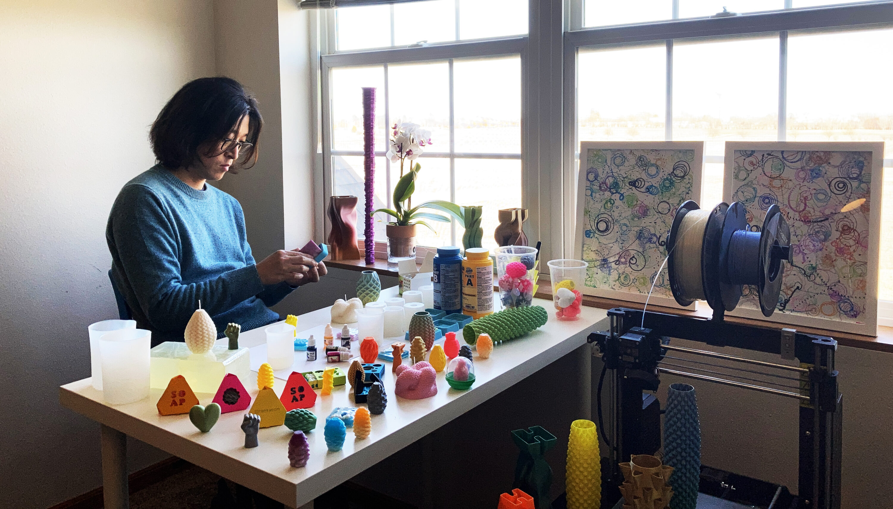 Taekyeom Lee working at his desk surrounded by 3d printed creations