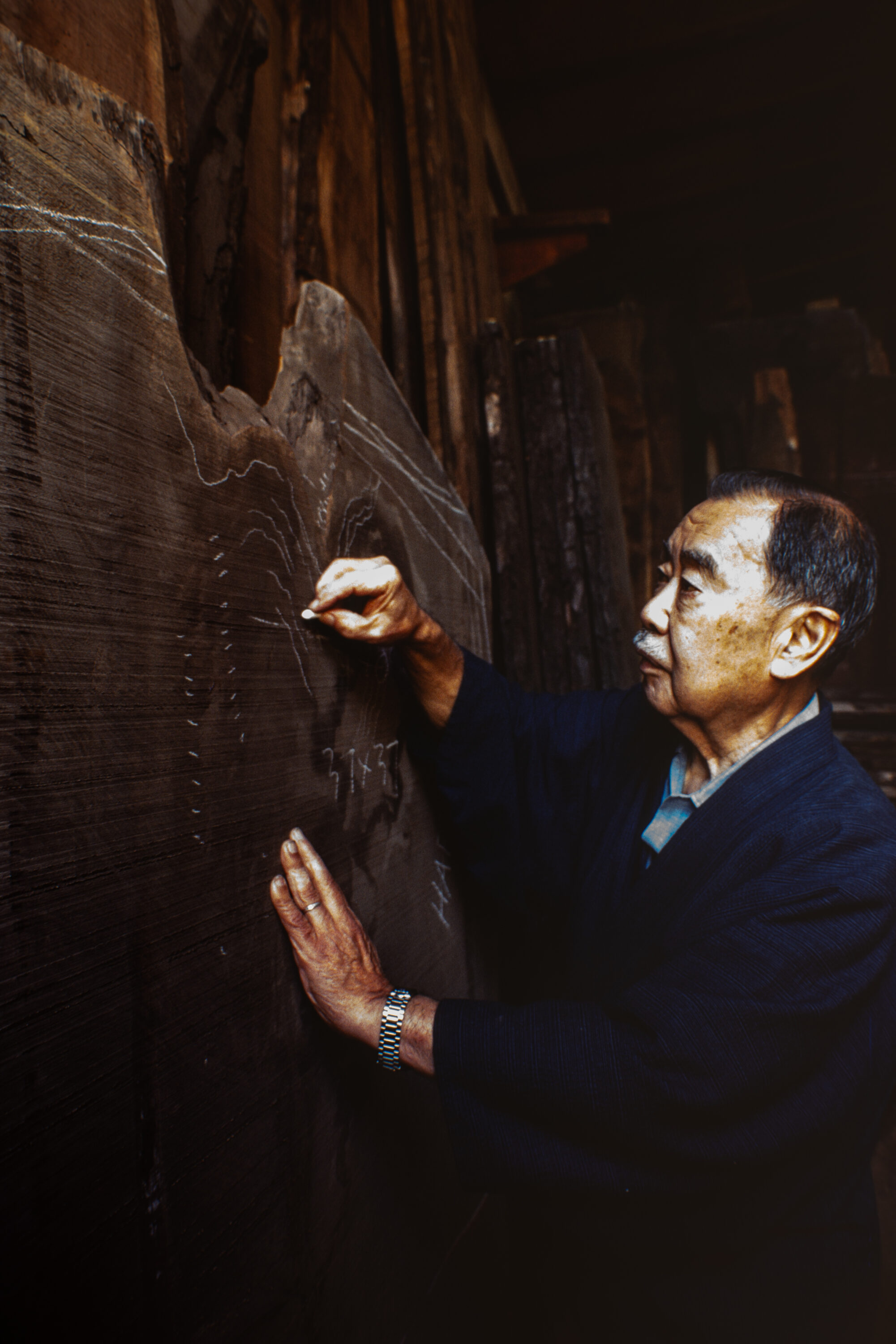 George Nakashima using chalk to mark a board in the rough. (Photo provided by Nakashima Woodworkers)