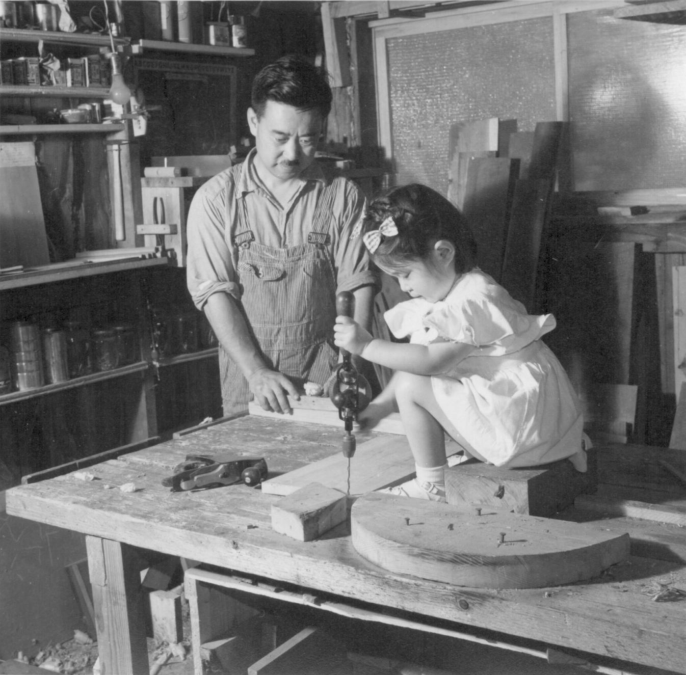 Mira as a child on top of the table with tools helping her father George